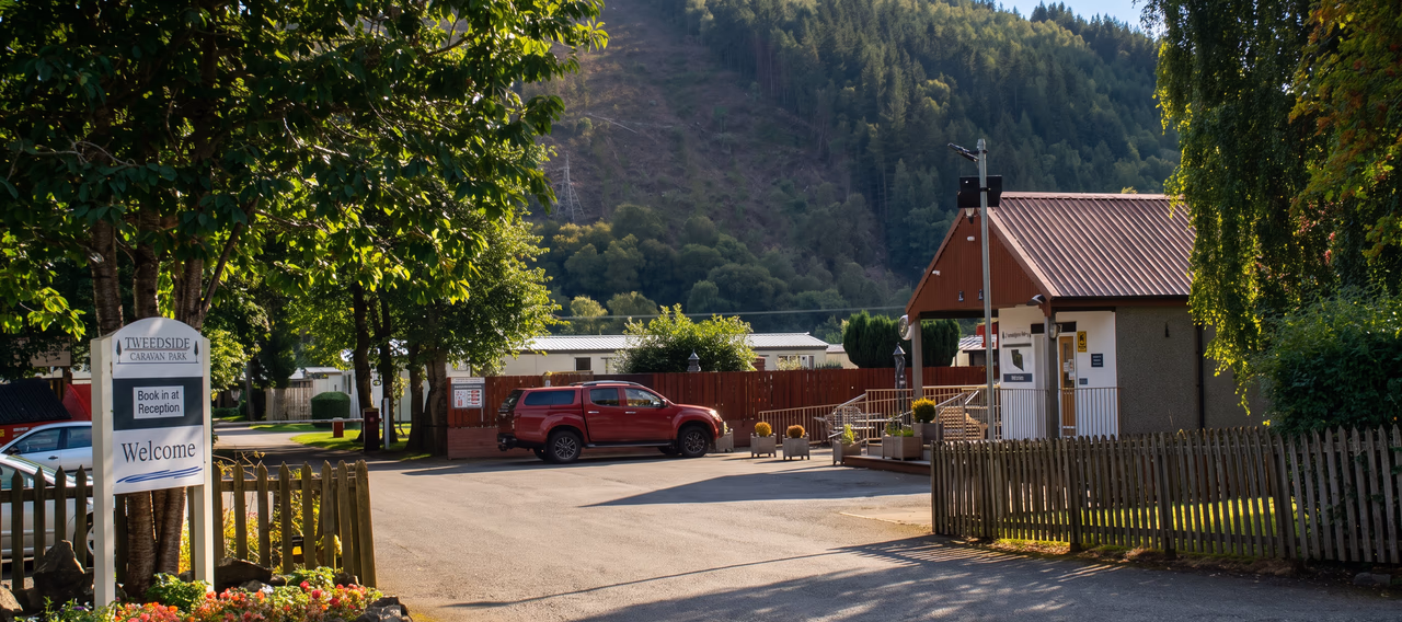 The entrance to Tweedside Caravan Park, with the welcome sign, flower bed and reception building