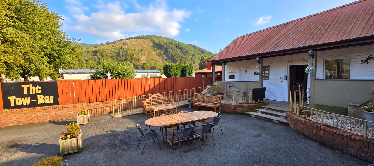The Tow-Bar seen from its outdoor seating area, with tables and chairs on the patio and hills behind