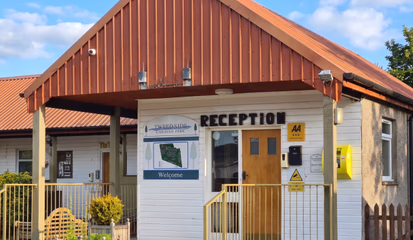 The reception and shop building, with RECEPTION above the door and the site map on the wall beside it