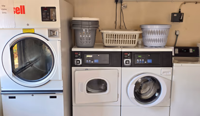 Washing machines and a tumble dryer in the on-site laundrette, with laundry baskets stacked on top