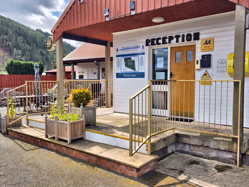 The reception building at Tweedside Caravan Park, with the welcome sign beside the door