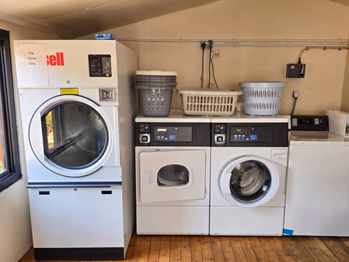 The on-site laundrette, with washing machines and a tumble dryer along the wall